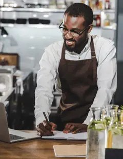 Multi-unit restaurant operator in apron reviewing financial documents to support location expansion