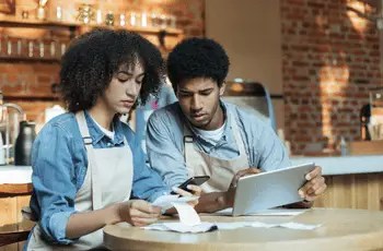 Two restaurant operators in aprons reviewing current financial systems and POS workflows during a TRIS Restaurant365 implementation discovery session