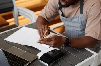 Restaurant operator in apron reviewing financial documents during a TRIS accounting discovery and assessment session