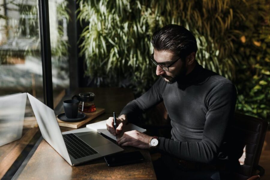 man in black sweater writing on a paper