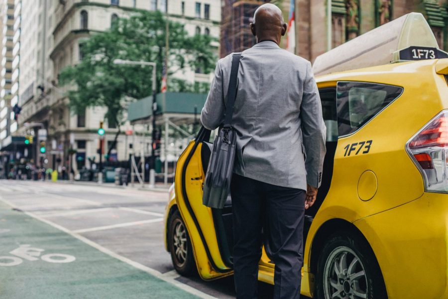 Why Have a Modern Messenger Bag in Transport? black man in stylish suit near taxi