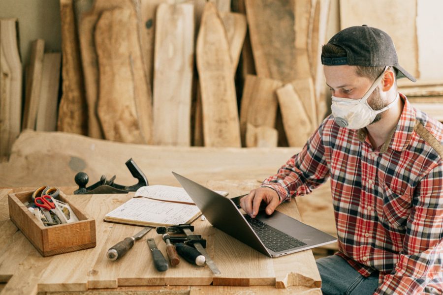 man using a laptop at a wood workshop - Best Selling Wood Projects on Etsy