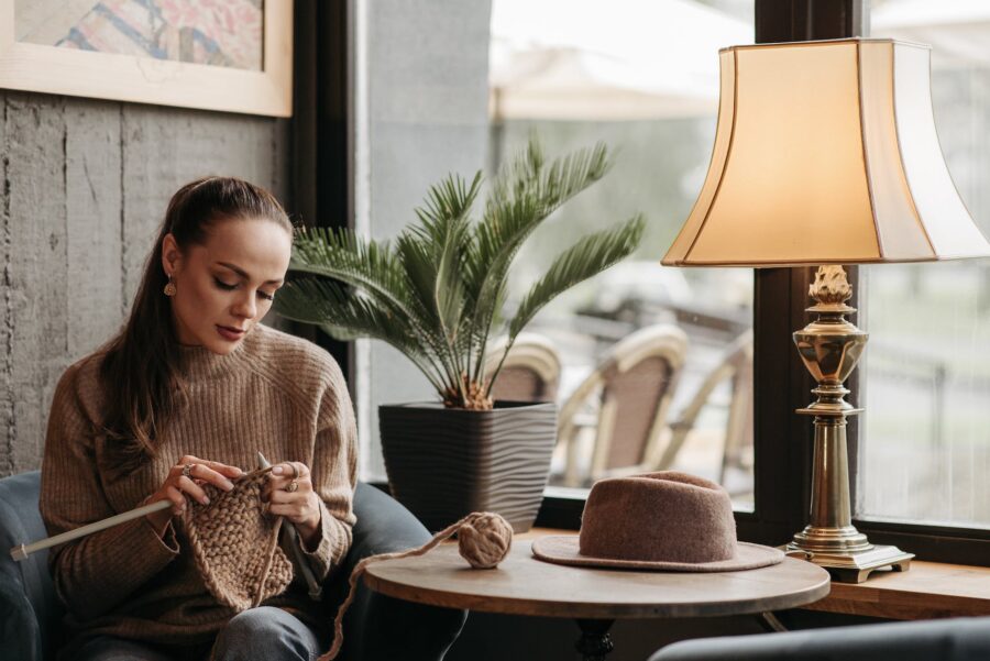 femme en pull tricotant à côté d'une fenêtre