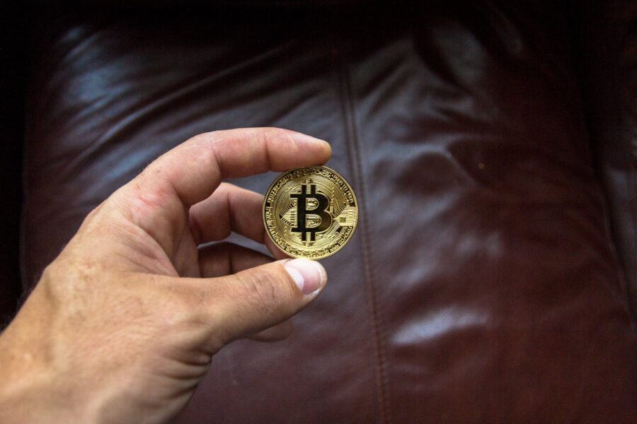 a man hand holding a round gold colored and black coin on person s hand showing bitcoin crypto