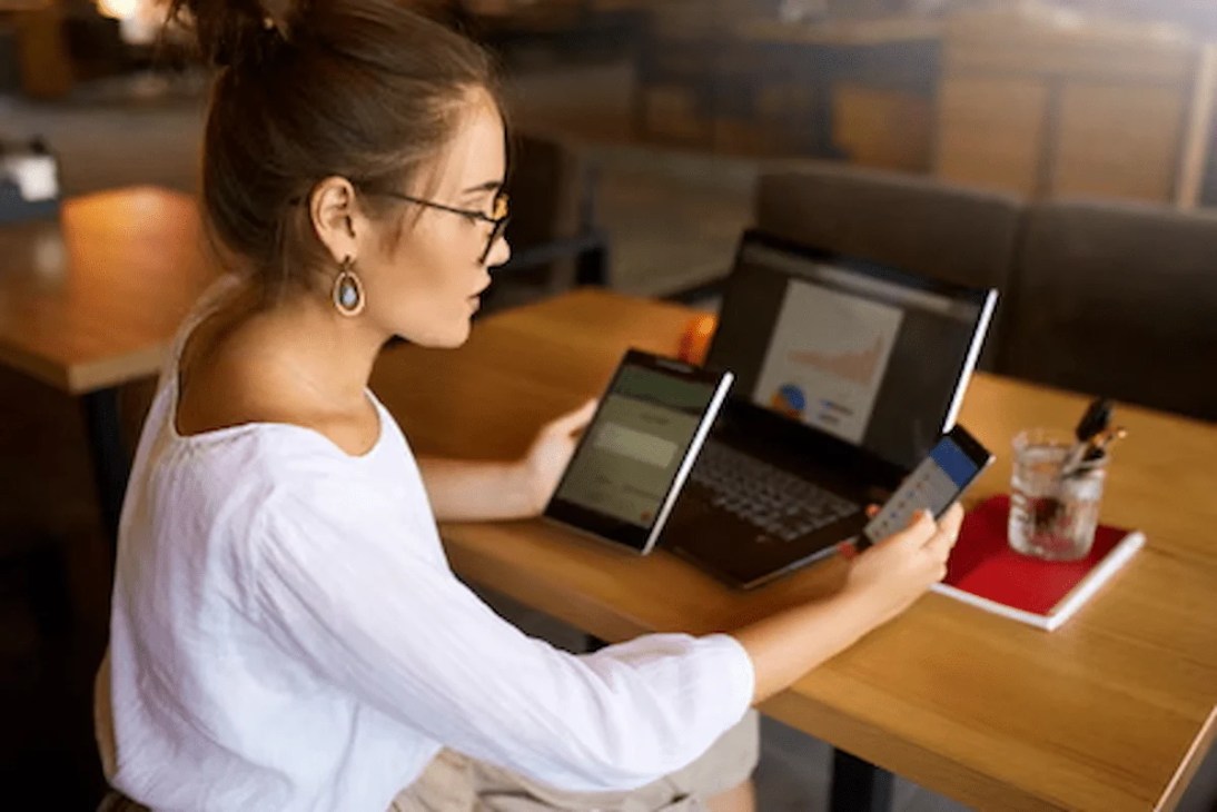 Content creator managing multiple devices—cellphone, laptop, and tablet—to stay connected across platforms.
