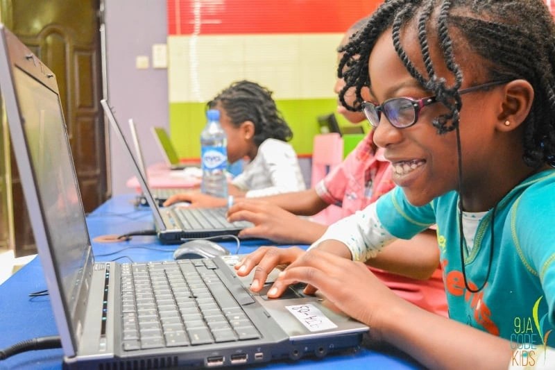 An African girl enthusiastically coding on her laptop, symbolizing youth taking charge of the continent’s digital future and building the next big platforms.
