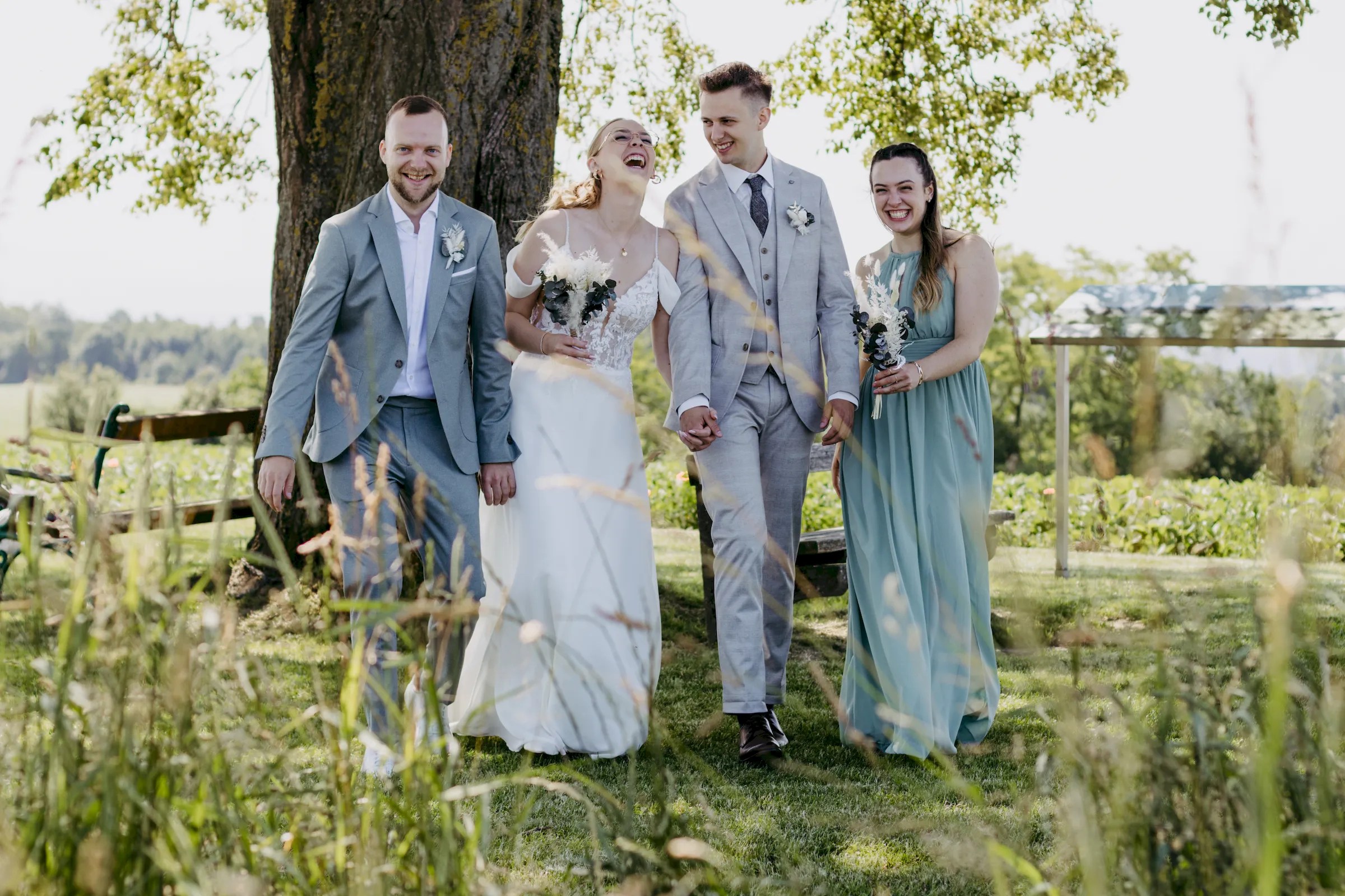 Brautpaar mit Trauzeugen unter einem großen Baum bei einer Sommerhochzeit
