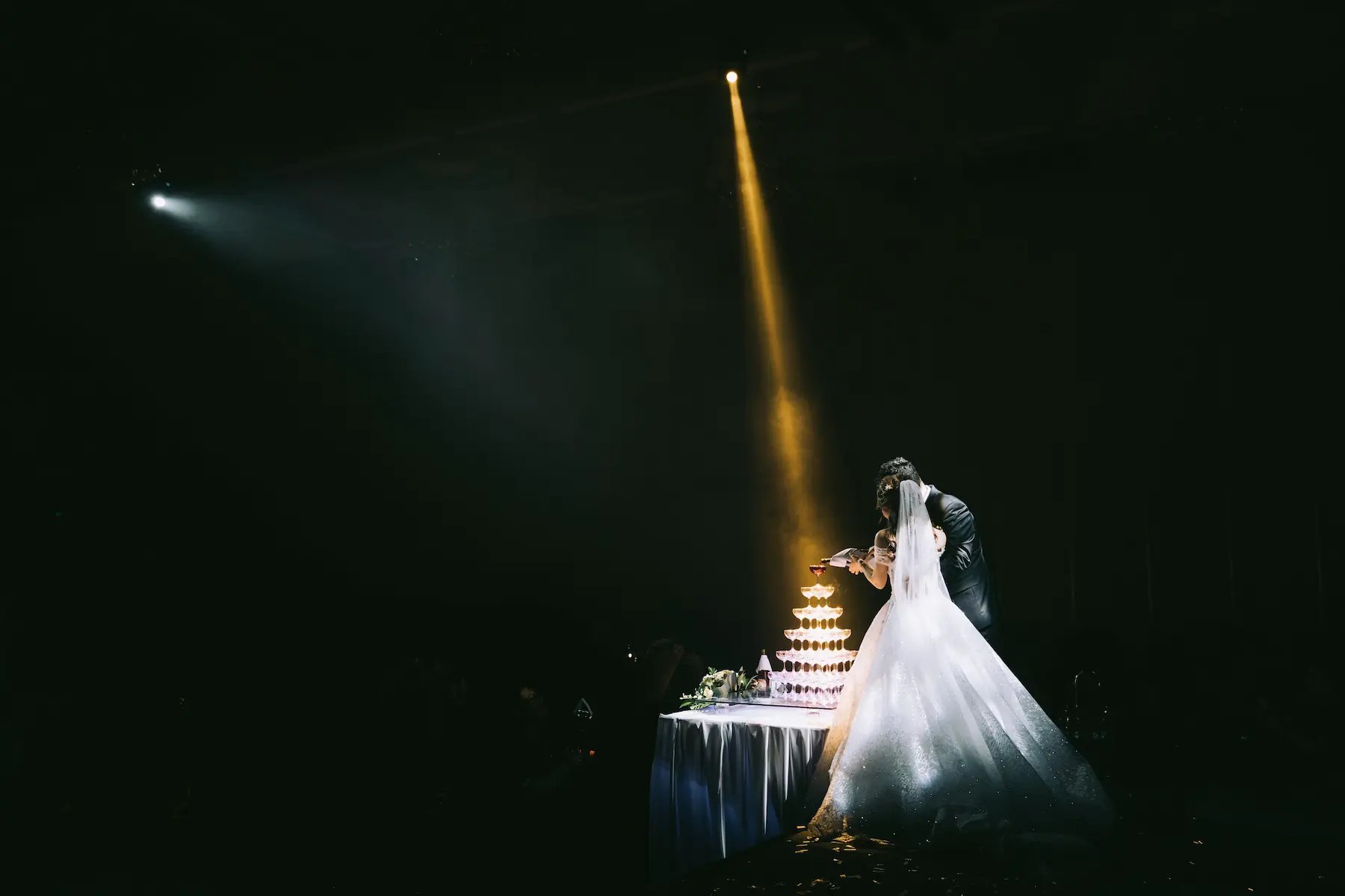 Pinspot lighting highlighting a wedding cake and florals on a reception table