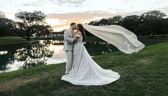 Bride and groom at sunset with her veil sweeping behind them, filmed by Weddings Unlimited