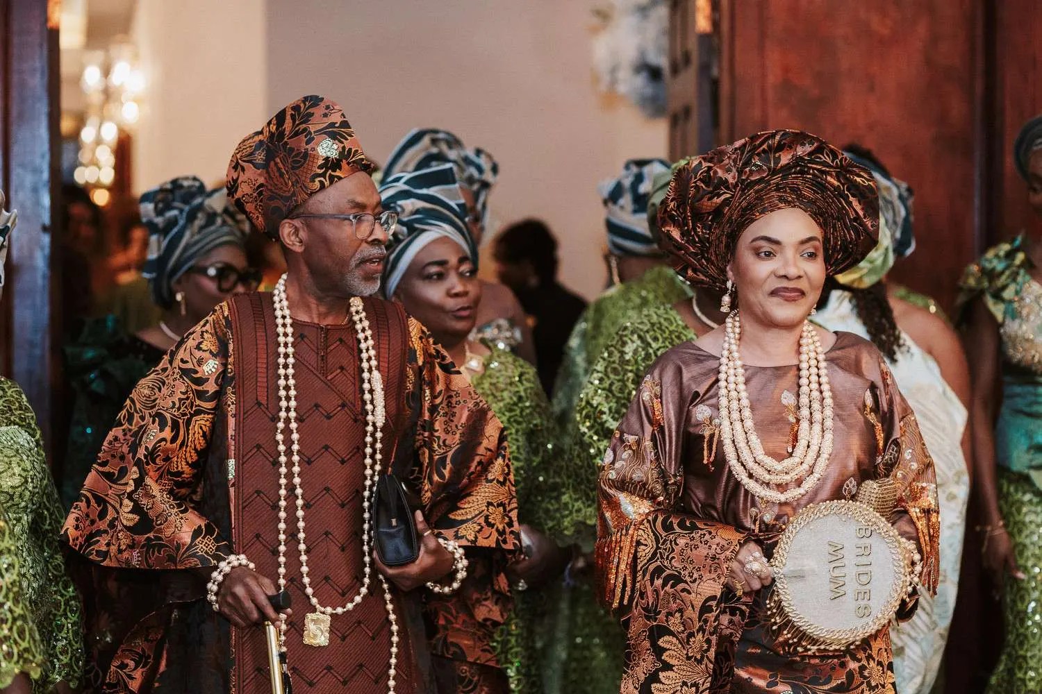 Elders and parents leading the drumming and dance entrance procession in coordinated fabric and pearls at a Nigerian wedding, photographed by Weddings Unlimited