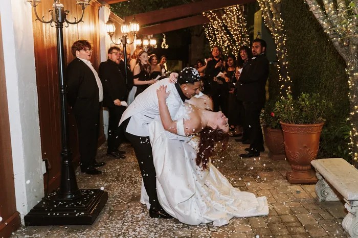 Bride and groom sharing a kiss during their wedding exit at The Bell Tower on 34th, Houston, TX