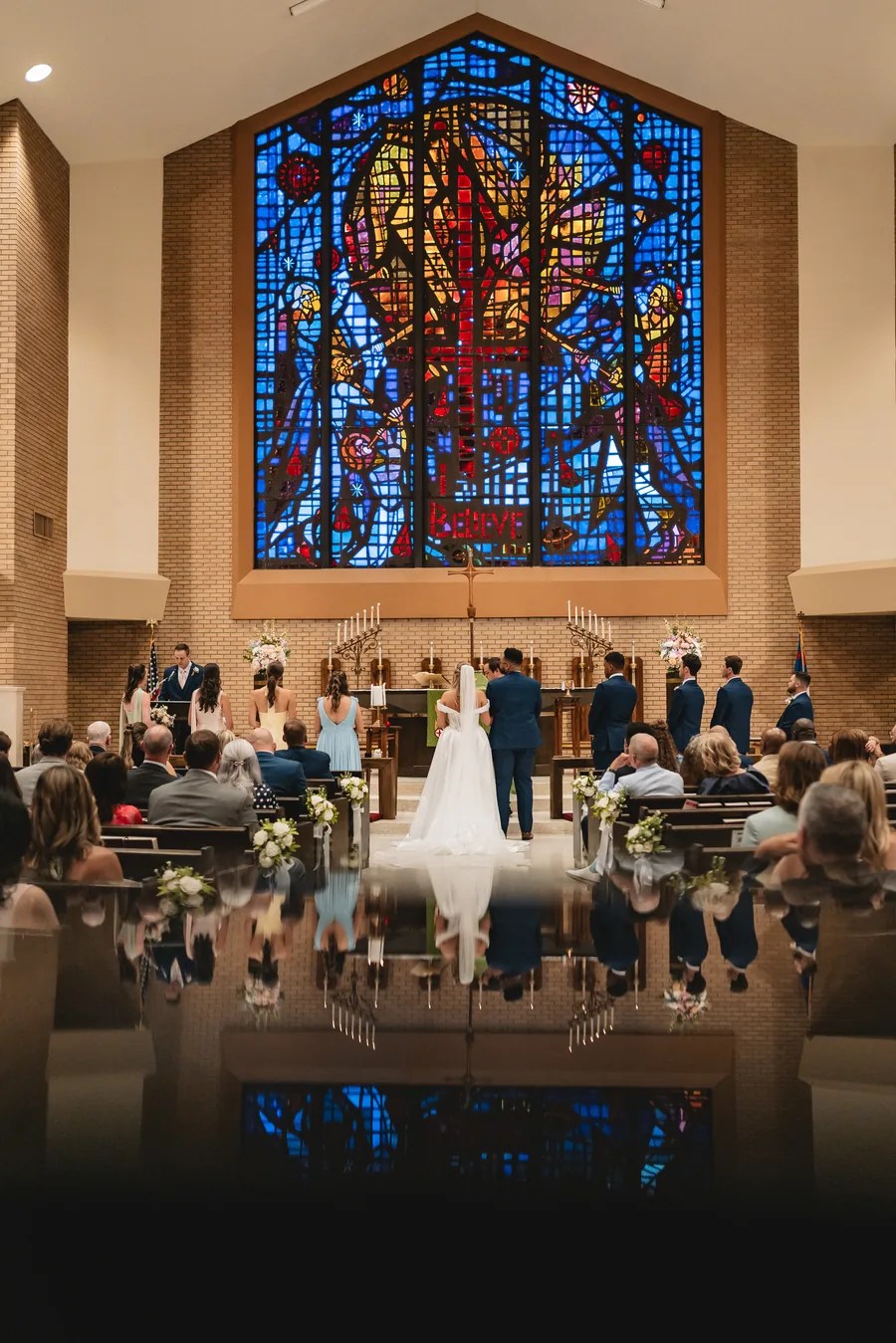 Church wedding ceremony beneath stained glass, photographed by Weddings Unlimited