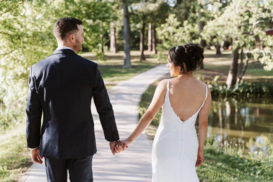 Bride and groom walking hand in hand along the pond path at Forever 5 Events, Conroe, TX