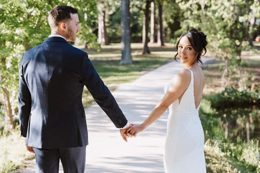 Bride glancing back at groom while walking at Forever 5 Events, Conroe, TX