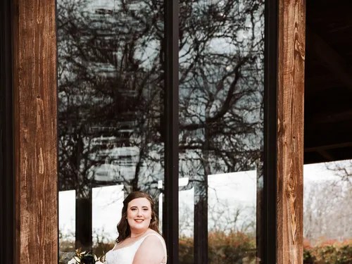 Bride posing by the wood-framed windows at The Springs Venue in Denton, Aubrey, TX