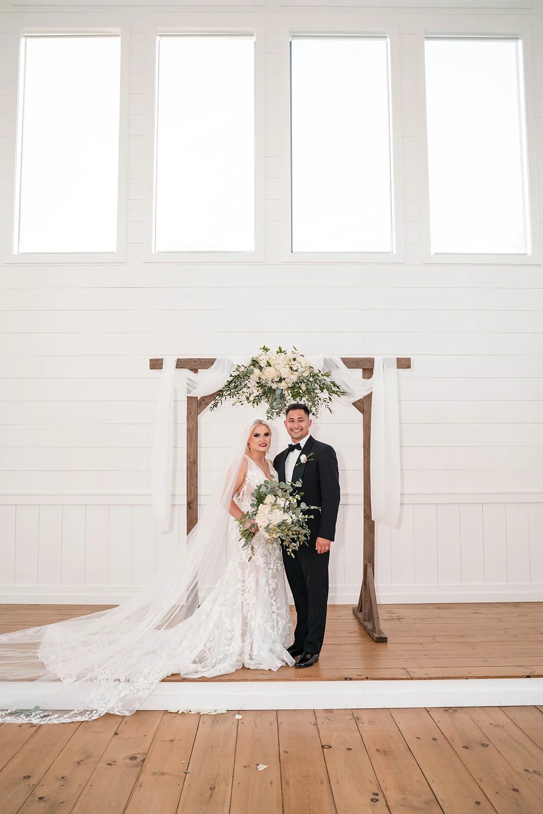 Couple at the wooden ceremony arch at Arrowhead Hill, Montgomery, TX