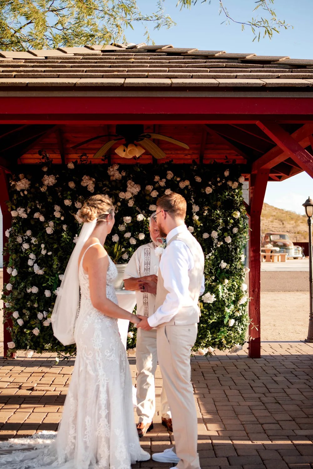 Bride and groom at the ceremony arch at Ashley's Backyard