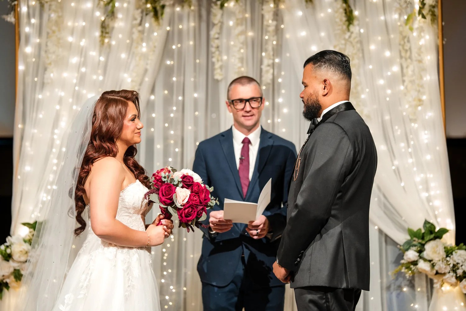 Vows under the string light drapes at Eden Events, Houston, TX