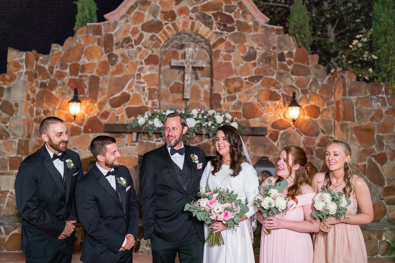 Bride and groom against the stone wall at Madera Estates in Conroe, TX