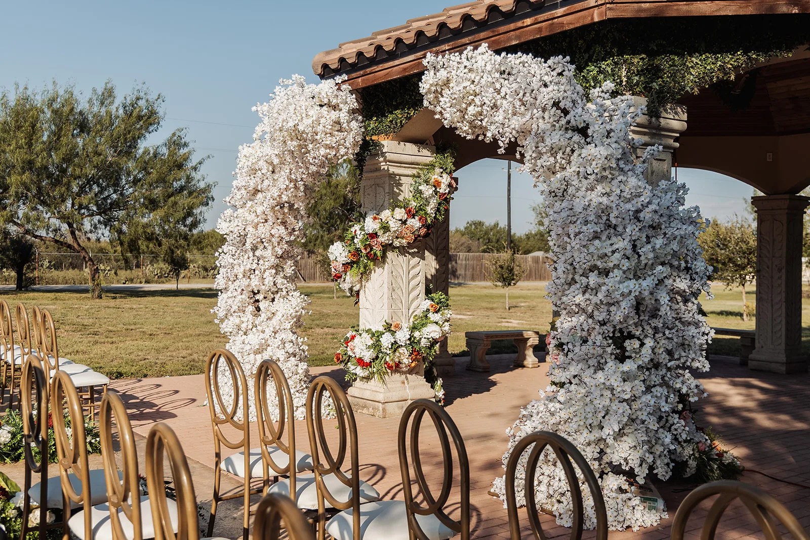 White floral arch in the stone courtyard at Monarca Event Center Edinburg