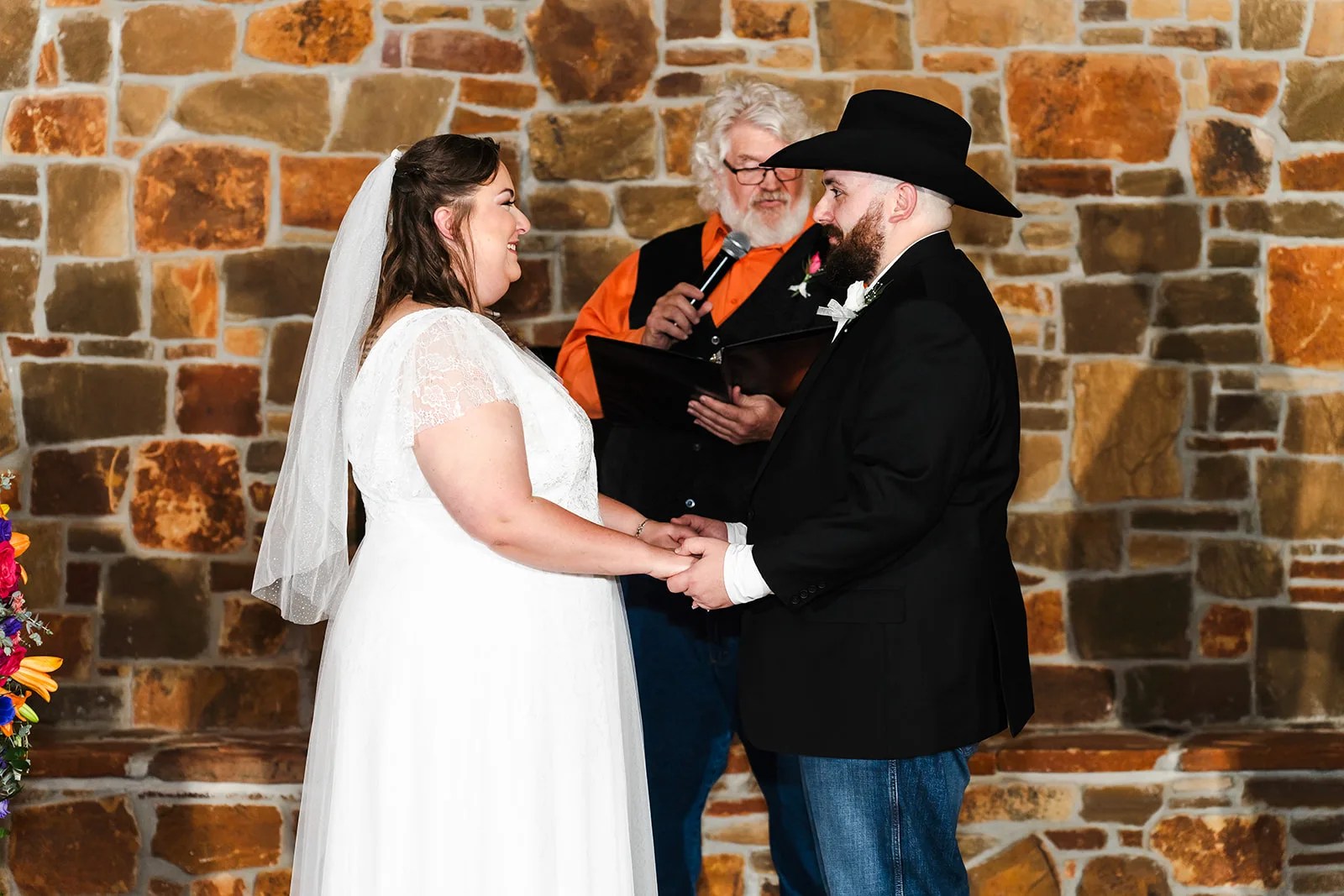 Bride and groom by the stone wall at Rustic Rose Events in Willis, TX