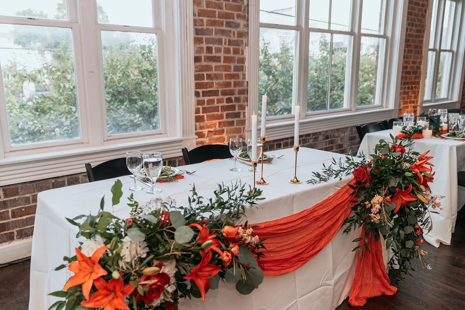 Head table with florals against the brick wall at Station 3 in Houston, TX