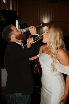 Bride and groom feed each other wedding cake with forks during indoor reception