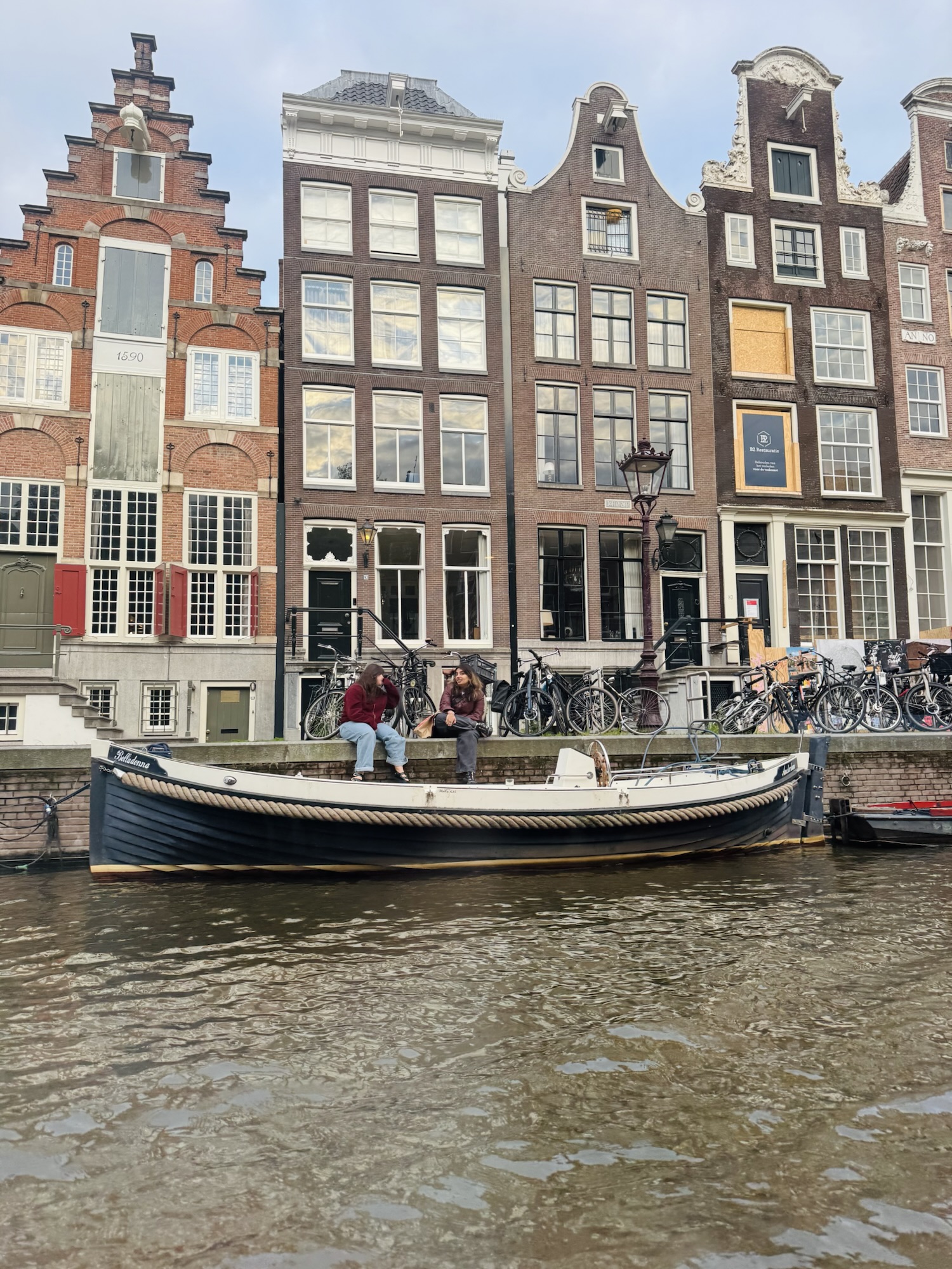 Girls sitting canal side in Amsterdam.