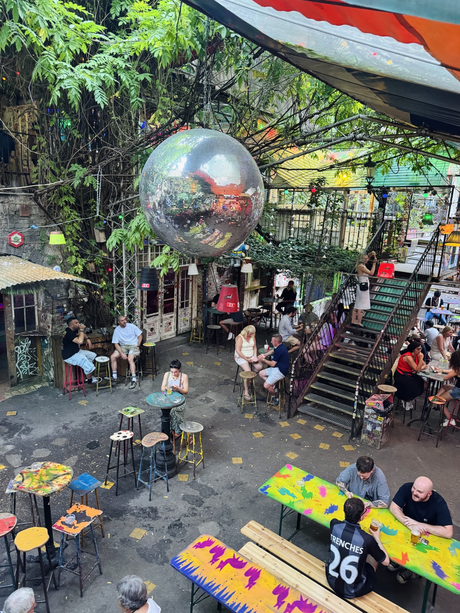 Patrons sitting under disco ball and hanging plants at Szimpla Kert