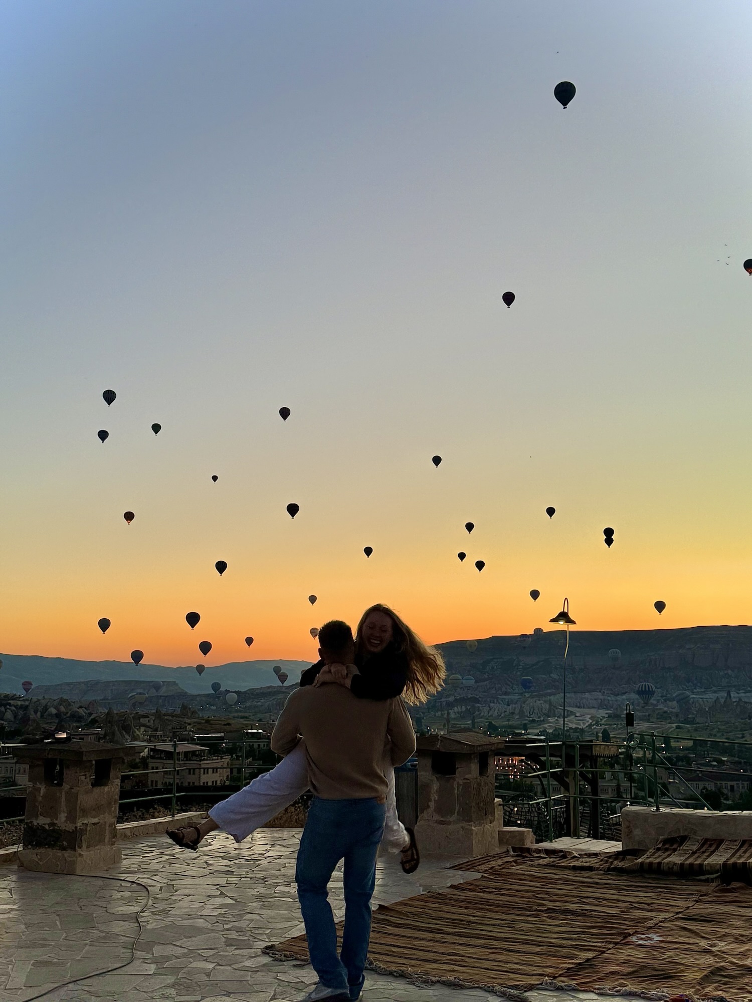 Couple on roof in front of hot air balloons in cappadocia