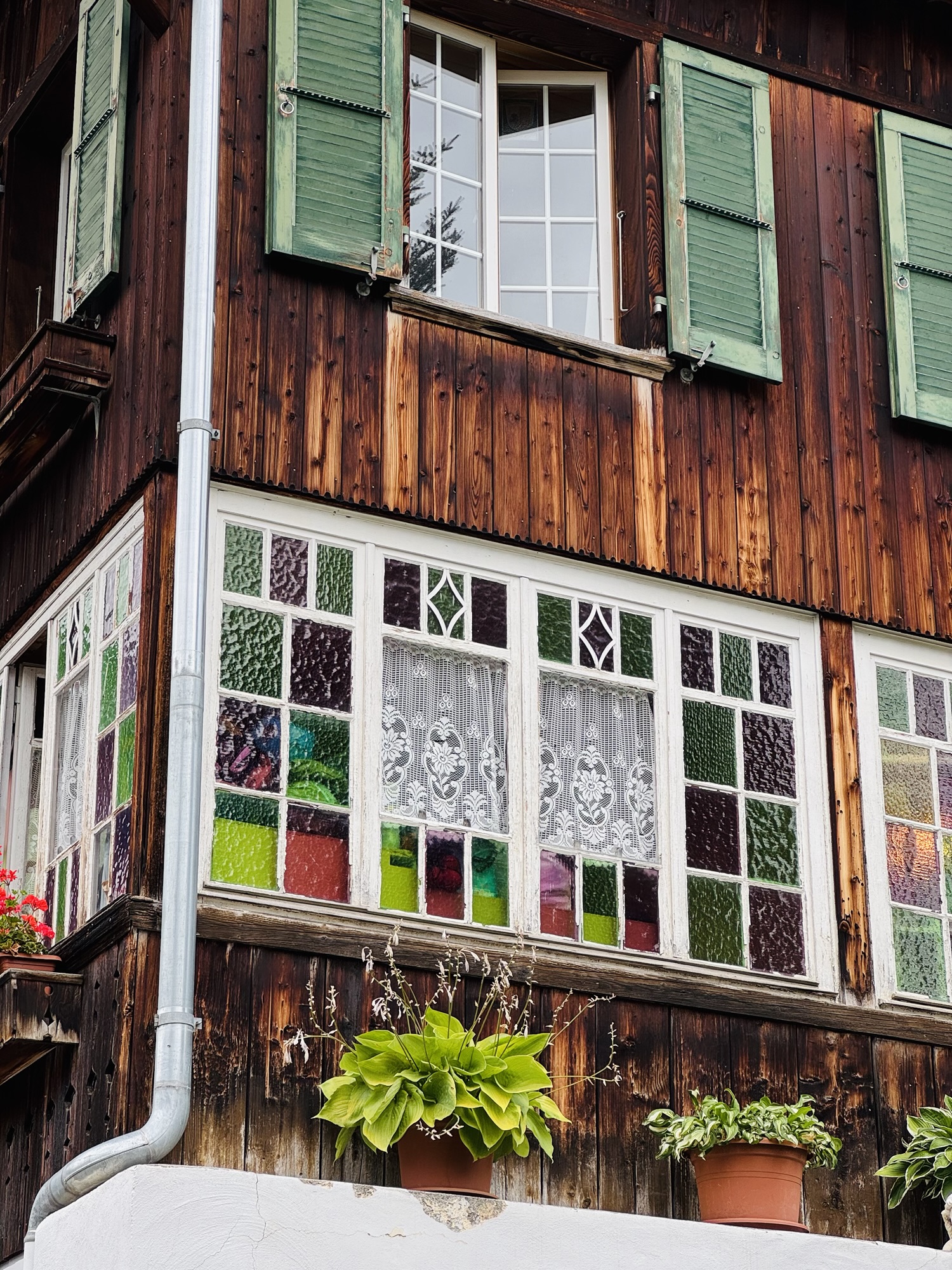 Swiss home in Murren Switzerland with green shades and colorful stained glass windows