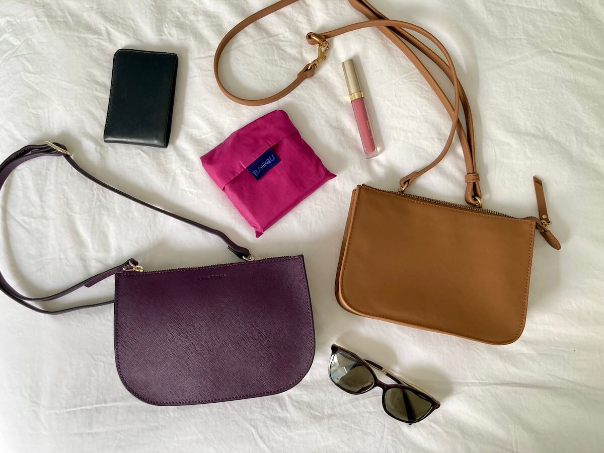 Two belt bags and various objects that may go in that bag, like sunglasses, wallet, lipstick, reusable bag.