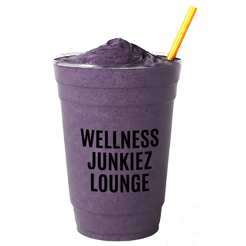 Slim Dealer mixed berry smoothie in a clear cup with Wellness Junkiez Lounge logo, yellow straw, and fresh blueberries, raspberries, strawberries, and blackberries on a white background.