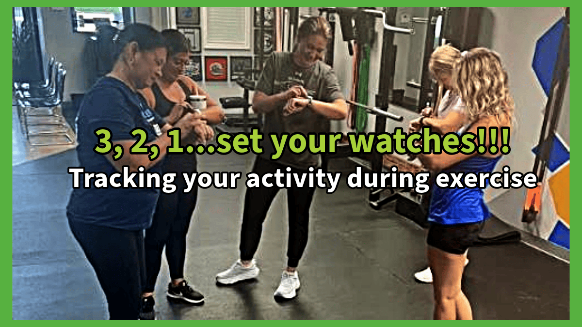 Five women in workout gear checking their smartwatches before exercising in a fitness space at Wellness Solutions Chiropractic in St. Louis County.