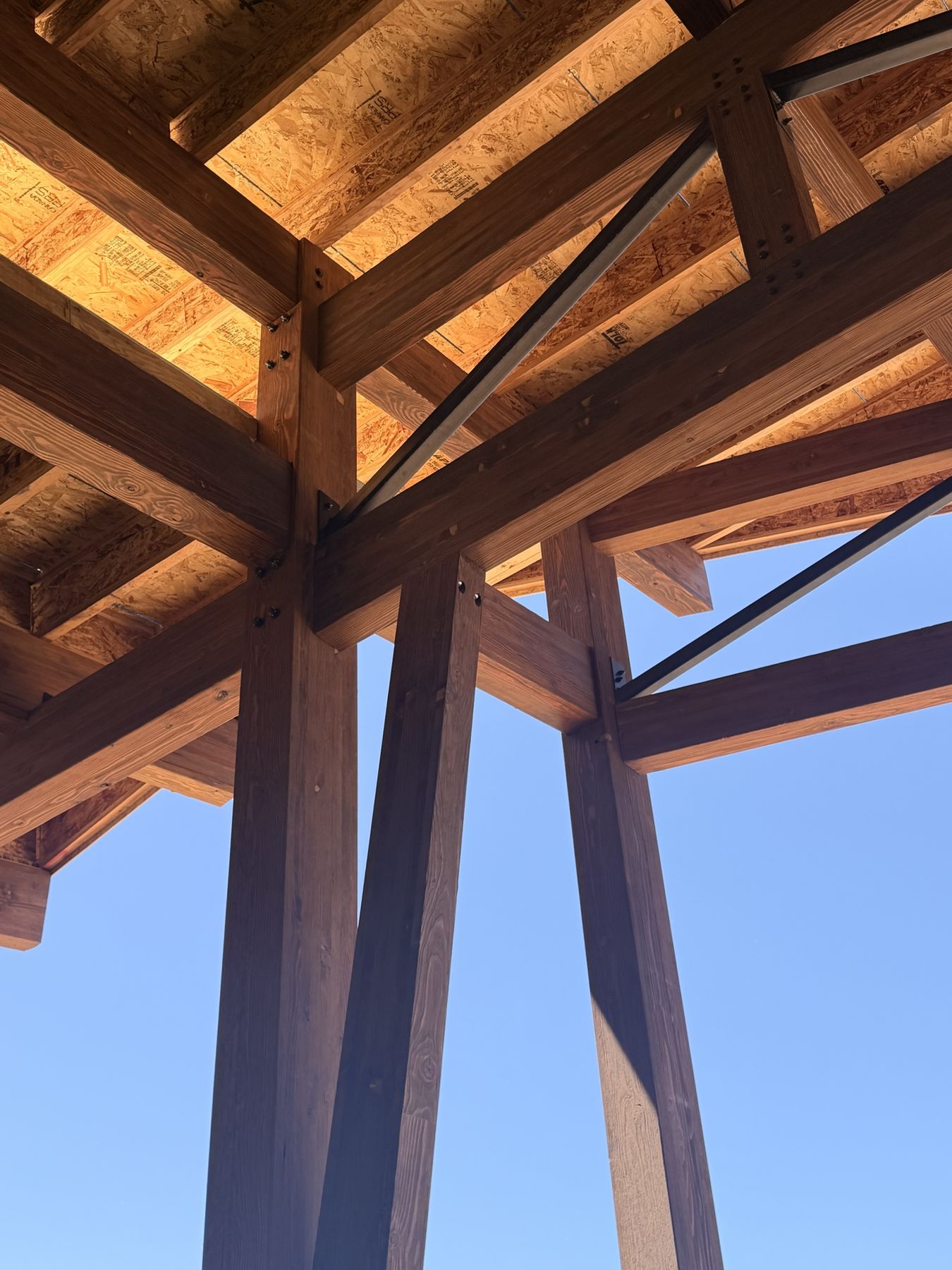 Timber posts and beams with steel connections against a blue sky