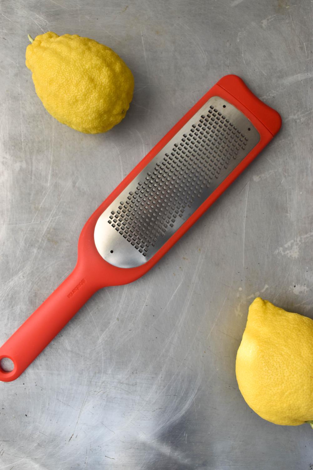 microplane and two lemons on gray surface