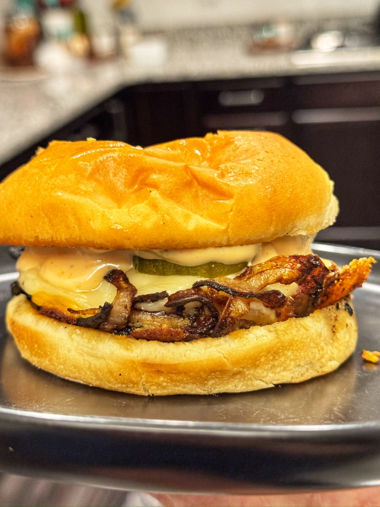 Oklahoma onion smash burger with melted cheese, caramelized onions, and pickles on a toasted bun