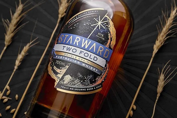Starward Two-Fold Double Grain Australian Whisky next to stalks of grain.