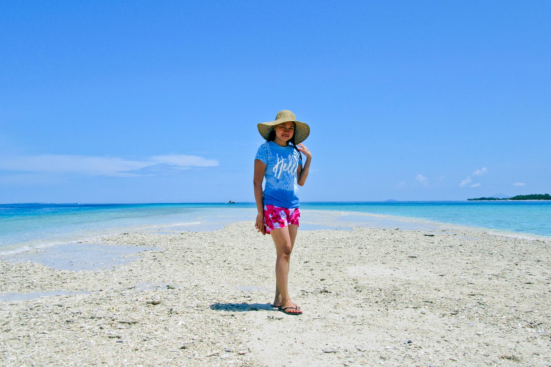 photo of woman standing on beach during daytime