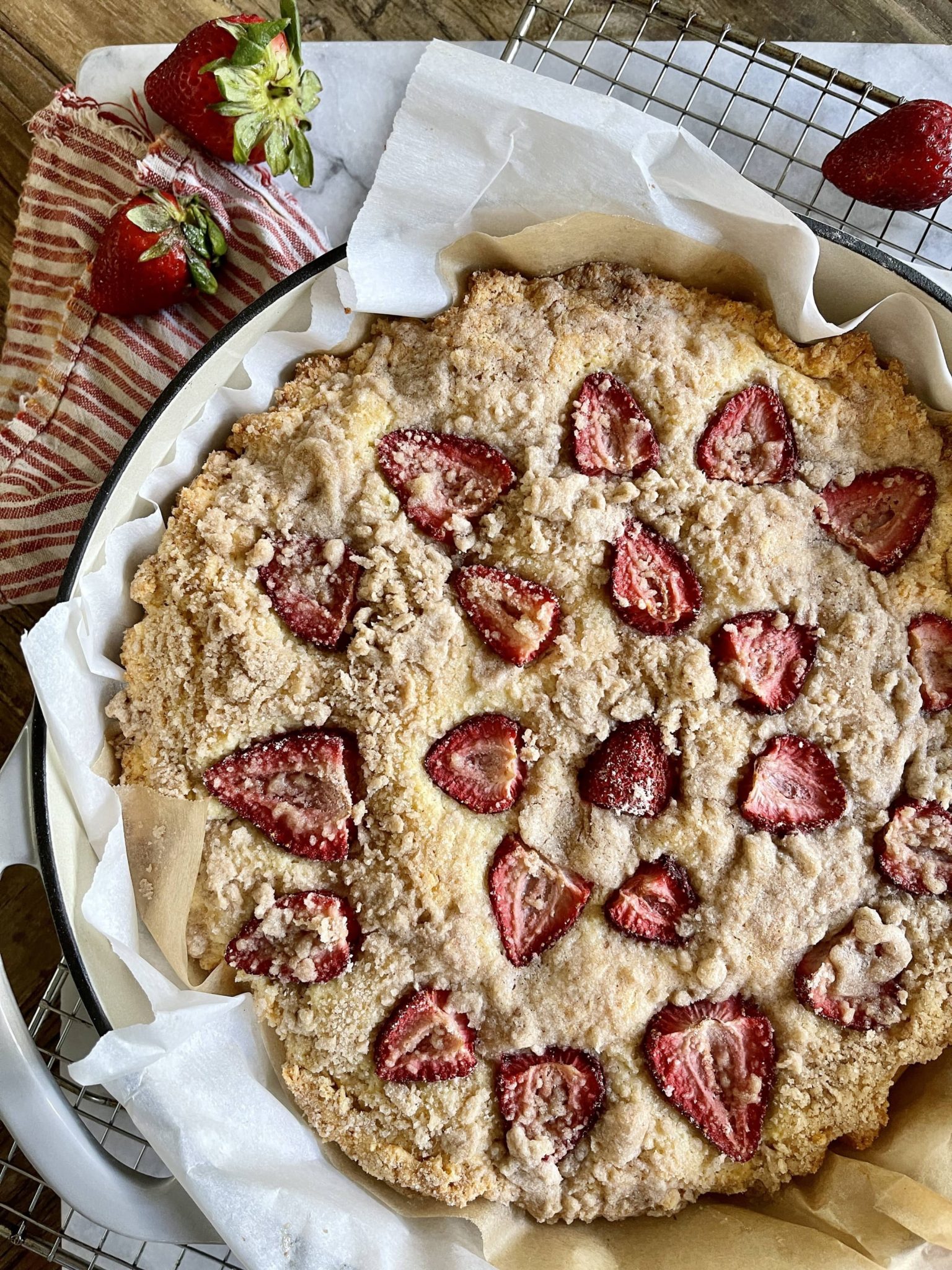 View of whole cake with red kitchen towel Gluten Free Sour Cream Strawberry Skillet Cake