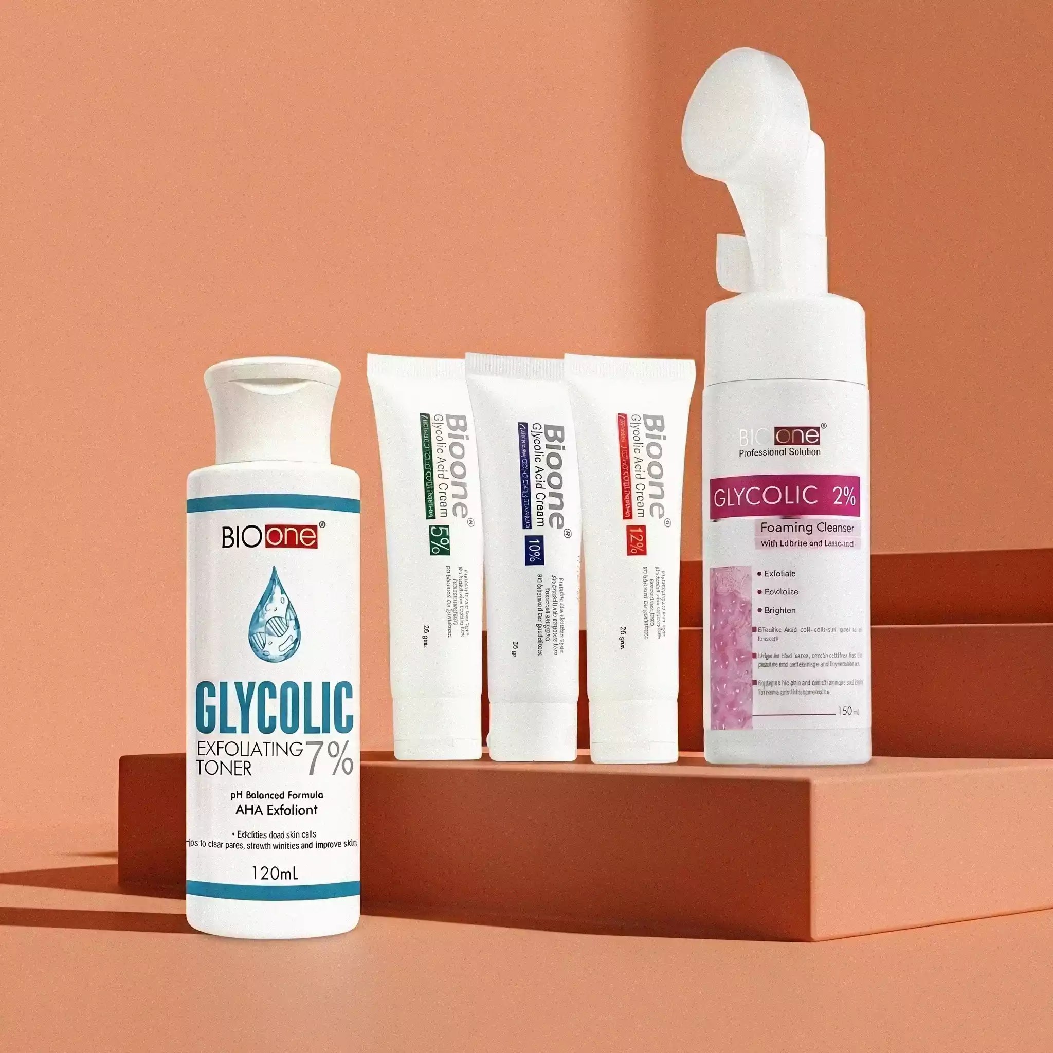 Complete bio one glycolic acid skincare range featuring glycolic exfoliating 7% toner, foaming cleanser with brush, and multiple treatment cream tubes displayed on peach stone steps