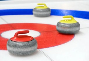 three curling sotnes on ice