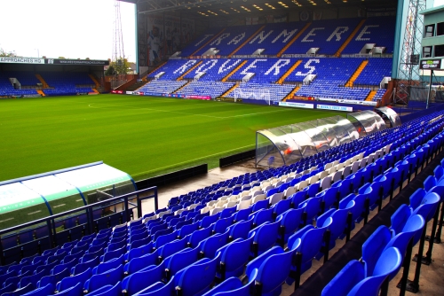 Image of Tranmere Rovers Home Ground Prenton Park with blue stadium tip up seating in the foreground, overlooking the pitch and the KOP stand which has written in the seats 'TRANMERE ROVERS' seating sold by willstack furniture co