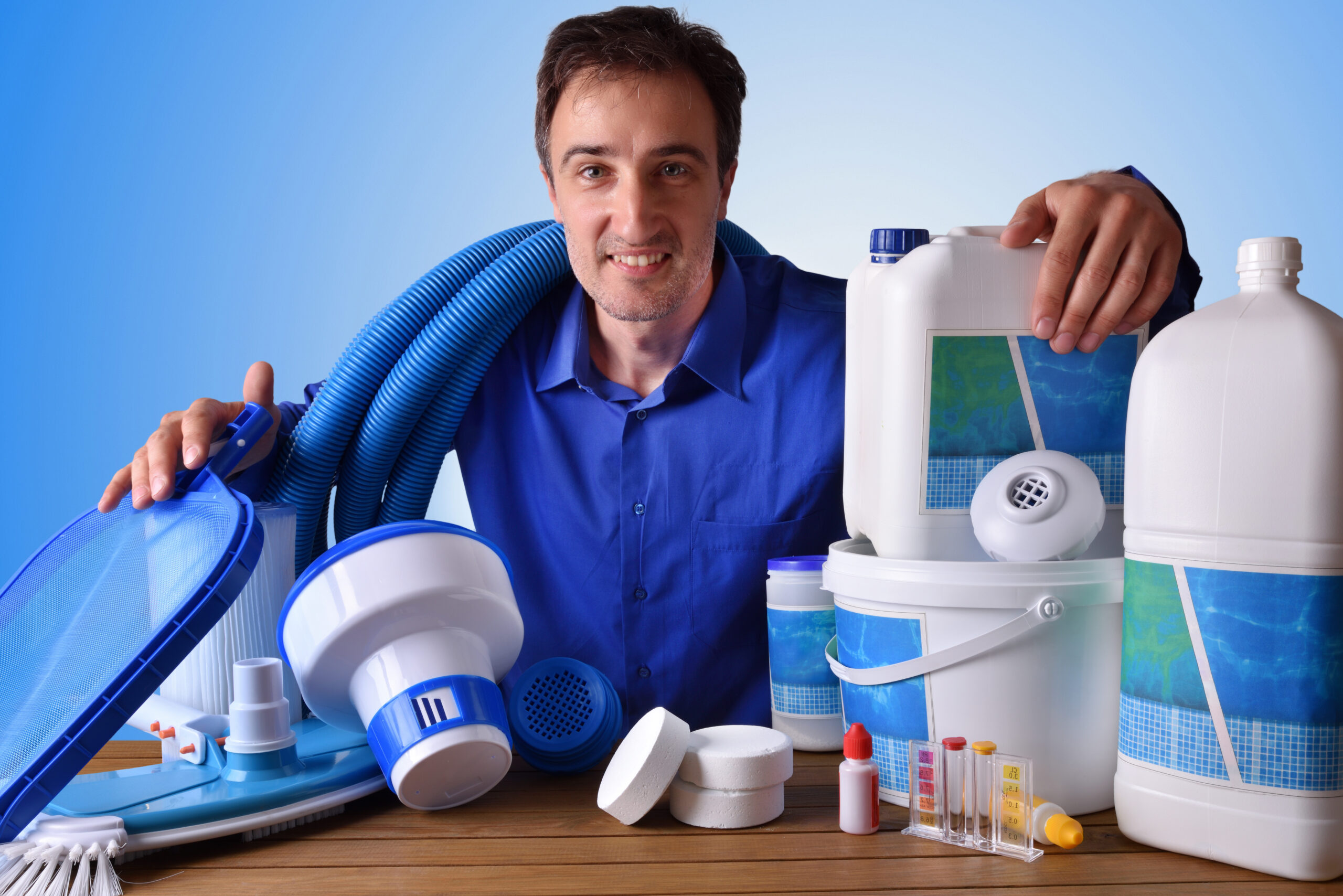 Swimming pool maintenance commercial with chemical cleaning products and tools on wood table and blue background. Horizontal composition. Front view