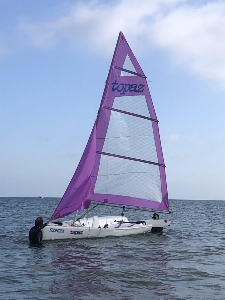Dos hombres arriando un velero en el mar