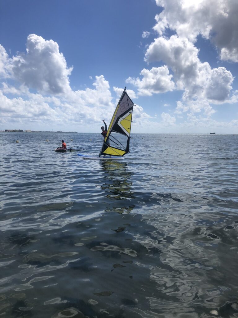 Mujer saludando mientras navega en windsurf en el mar
