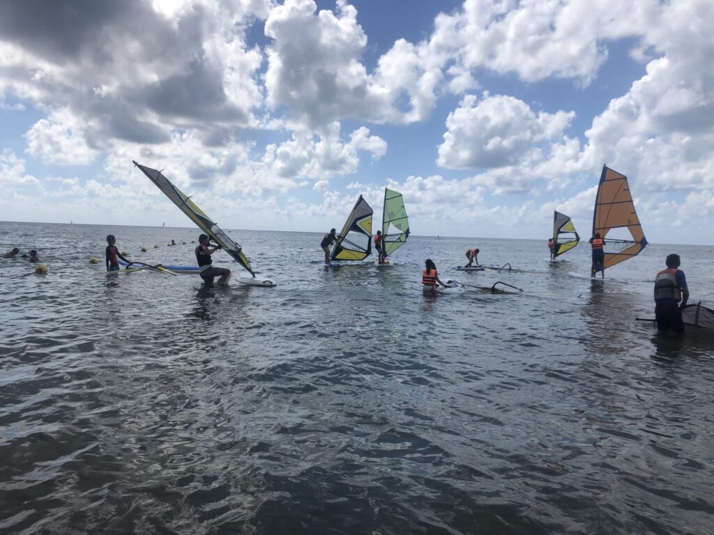 Grupo de personas aprendiendo windsurf en verano