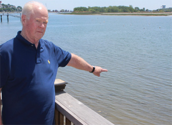 Dick Lawton points to one of the locations adjacent to the Cottage Park Yacht Club where the Massachusetts Oyster Project will be placing clean oyster shells this Saturday. He is encouraging local residents to participate in the project.