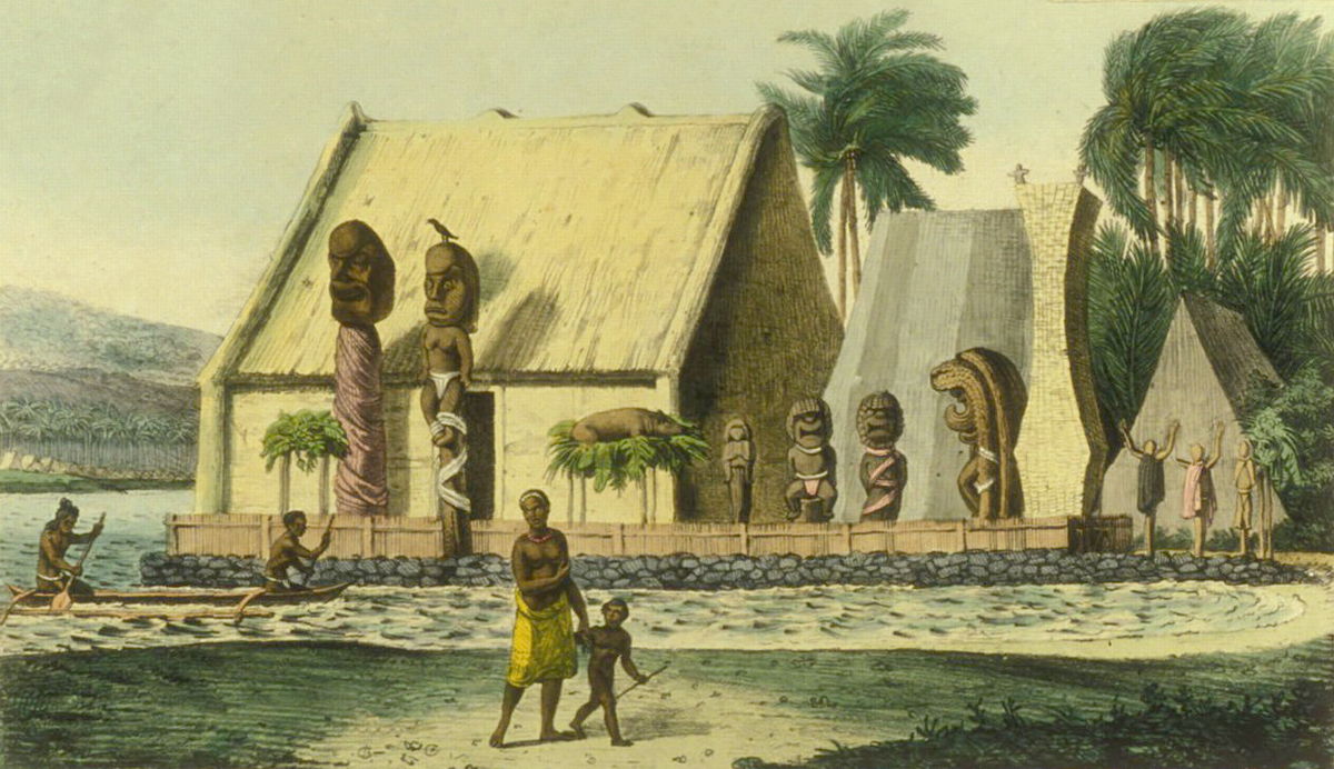 A village scene with thatched-roof buildings surrounded by large carved statues, palm trees in the background, people walking, and a canoe on the water in front.