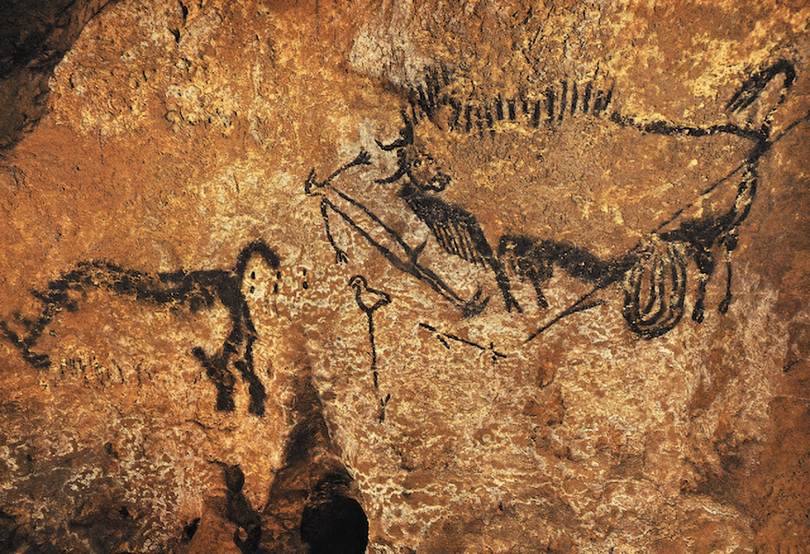Ancient cave painting showing a large bull with long horns and a human figure with a spear, along with another animal, on a rough, reddish-brown rock surface.